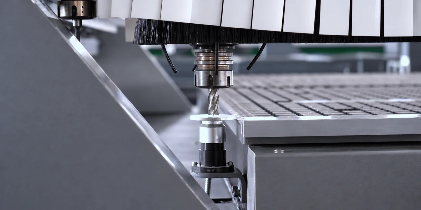 Router CNC Start ATC 10 S em perspectiva, com a mesa de descarga na frente, a mesa de trabalho com a chapa sob o pórtico, o comando Syntec com tela e teclado no braço lateral e o volante MPG pendurado no cabo